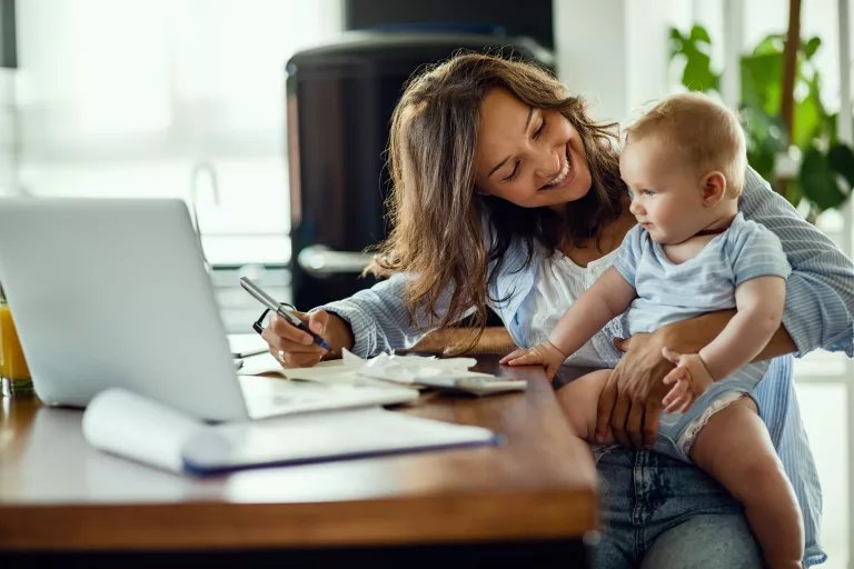 Happy mother talking to her baby while working at home